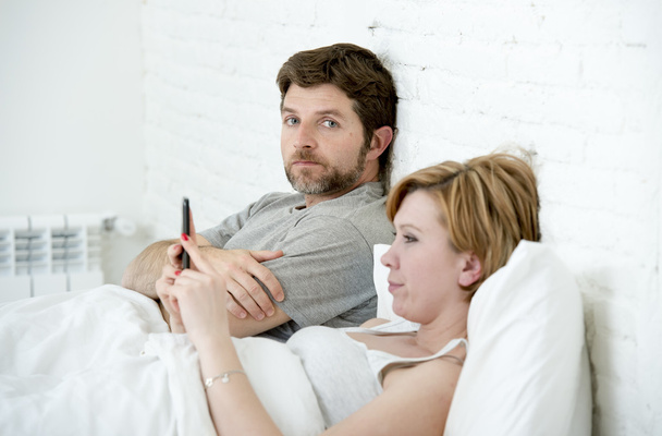 couple in bed husband frustrated upset unsatisfied while wife using mobile phone  - Photo, Image