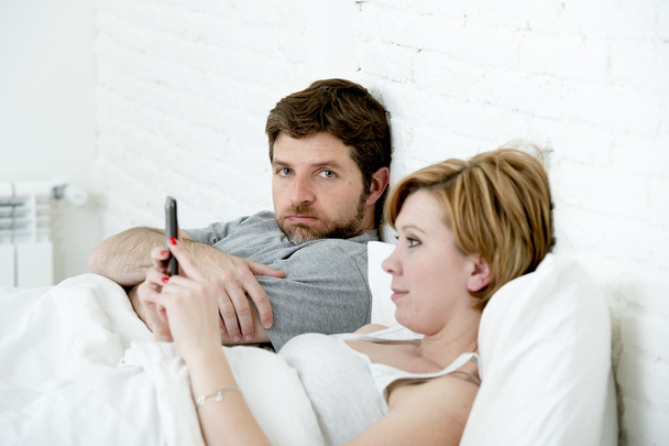 ζευγάρι στο κρεβάτι σύζυγος απογοητευμένοι αναστατωμένος ανικανοποίητος ενώ η γυναίκα που χρησιμοποιούν κινητό τηλέφωνο  - Φωτογραφία, εικόνα