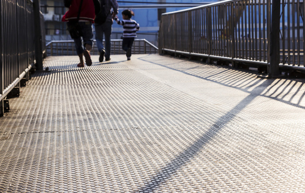 Familia caminando en el paso elevado de acero
 - Foto, Imagen