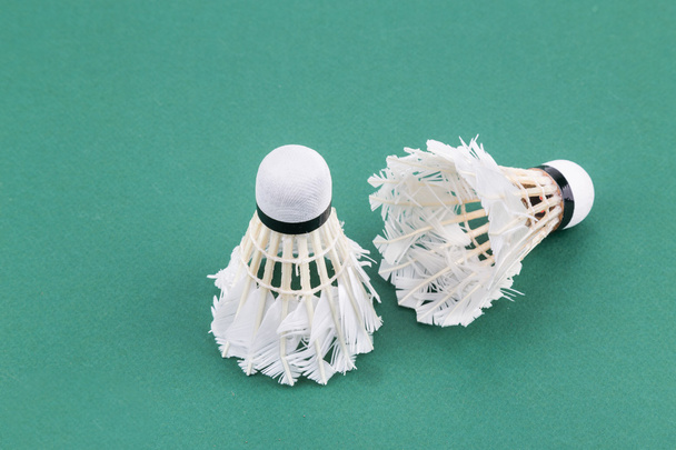Twee worned uit gebruikte badminton shuttle op groene Hof mat - Foto, afbeelding