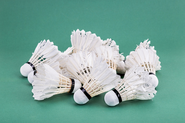 Hoopjes van gebruikte en worned uit badminton shuttle op groene cour - Foto, afbeelding