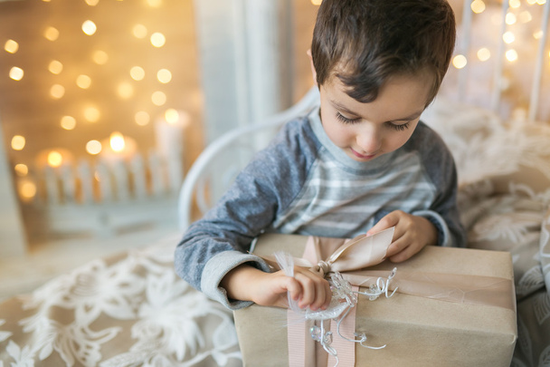 Porträt eines kleinen Jungen öffnet ein Weihnachtsgeschenk - Foto, Bild