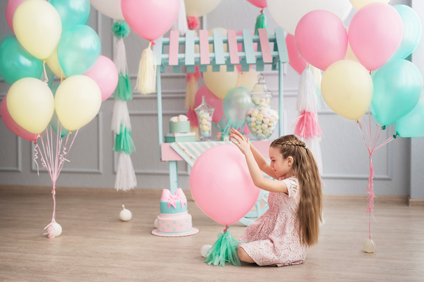 Kis lány ül a stúdióban díszített színes ballonok - Fotó, kép