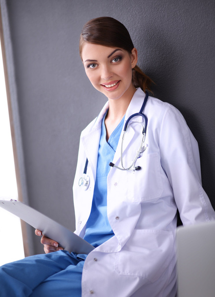 Female doctor working sitting on gray  background - Photo, Image