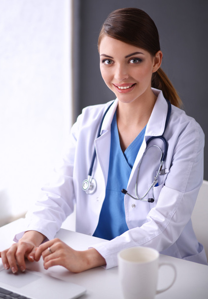Femme médecin travaillant assis sur fond gris - Photo, image