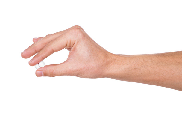 Рука мужчины держит две таблетки между большим и указательным пальцами изола
 - Фото, изображение