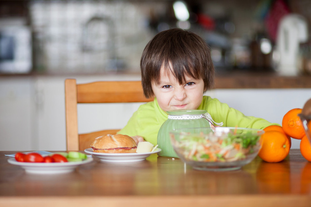 Beautiful little boy, eating sandwich at home - Фото, зображення