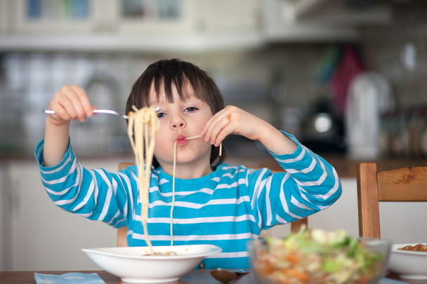 Cute little boy, eating spaghetti at home for lunchtime - Фото, зображення