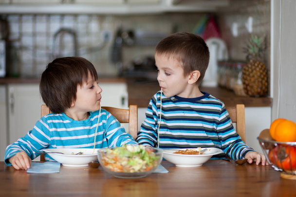 Two sweet children, boy brothers, having for lunch spaghetti at  - Foto, afbeelding