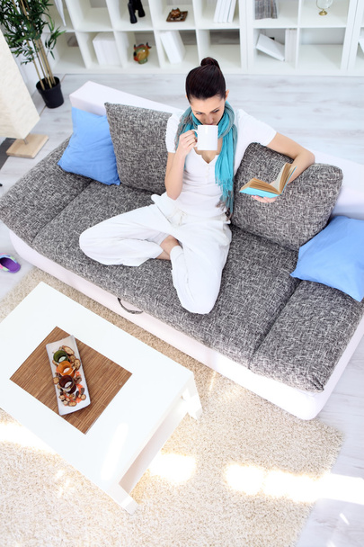 Relaxation woman with tea and book in living room - Fotoğraf, Görsel