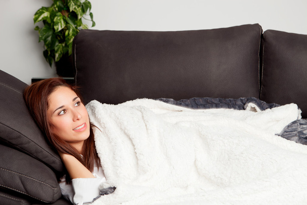 молодая девушка лежит на диване, покрытый одеялом
 - Фото, изображение
