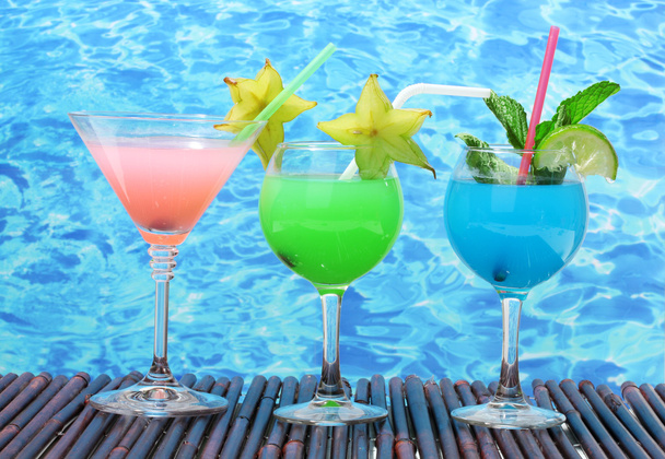 Glasses of cocktails on table on blue sea background - Photo, Image