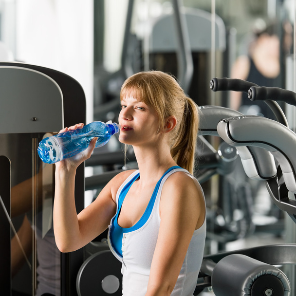 Woman drink water at fitness machine - Foto, afbeelding