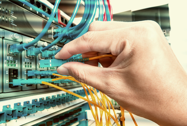 χέρι με ινών καλώδια δικτύου συνδεδεμένοι σε servers στο ενός datacen - Φωτογραφία, εικόνα