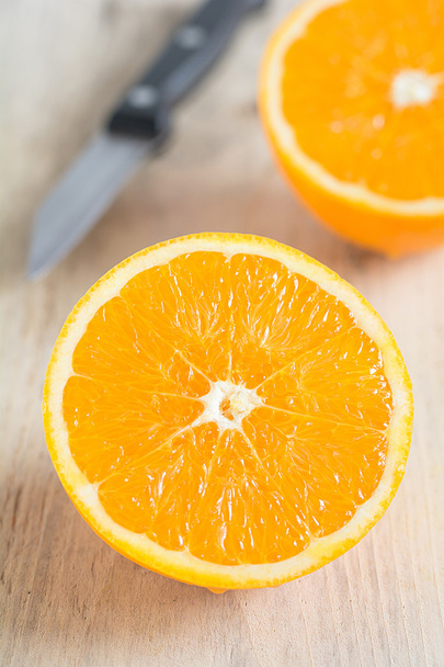 Uma laranja cortada jaz em um tabuleiro
 - Foto, Imagem