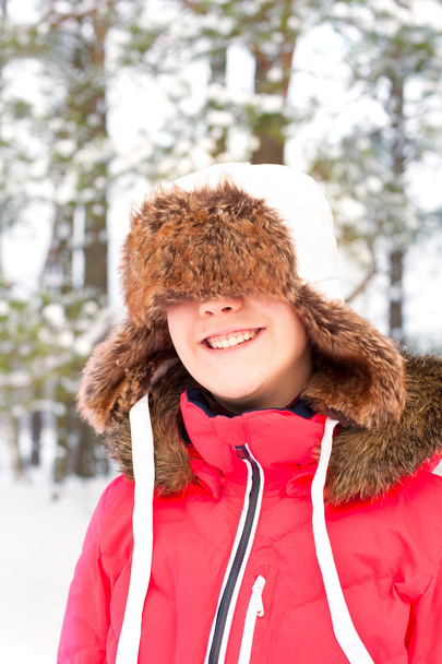 Funny cheerful laughing girl in warm earflap in winter forest - Photo, Image