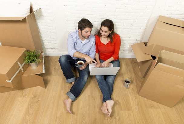 couple assis sur le sol se déplaçant dans une nouvelle maison en choisissant des meubles avec ordinateur portable
 - Photo, image