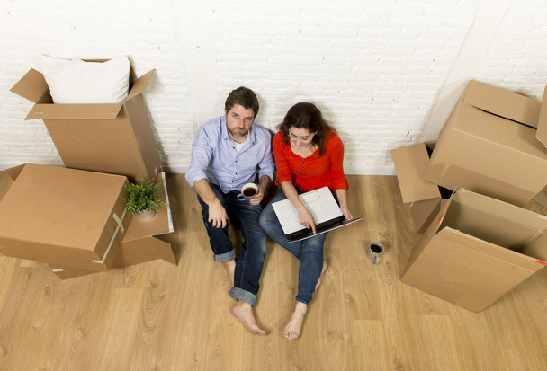 пара, сидящая на полу, переезжая в новый дом, выбирая мебель с ноутбуком
 - Фото, изображение