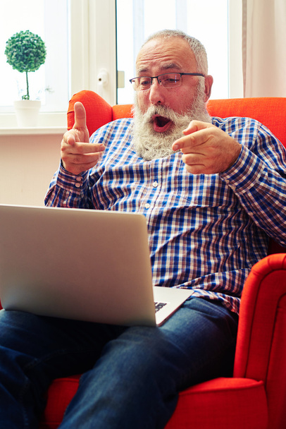 hombre sentado en la silla y apuntando a la computadora portátil
 - Foto, Imagen