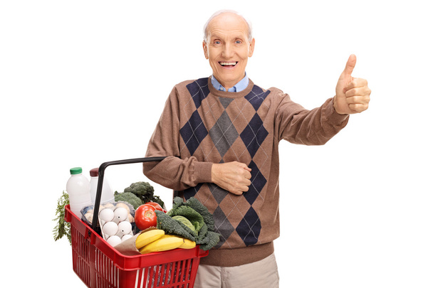 Senior man with basket and giving thumb up - Foto, Imagen