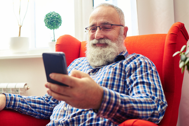 man resting on the chair with smartphone at home - Foto, immagini