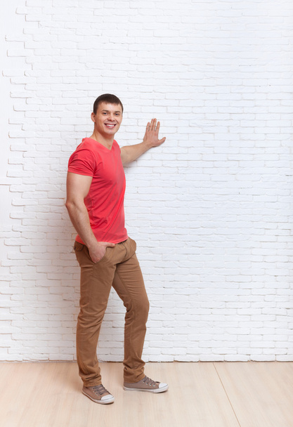 Young Man Smiling Standing Hand On Wall Copy Space - Foto, afbeelding