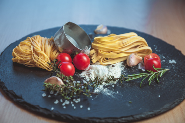 Bela espaguete fresco no quadro negro com especiarias e tomates
 - Foto, Imagem