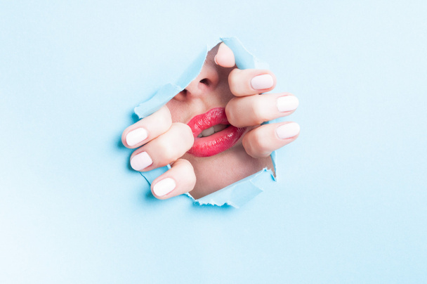 attraktiver weiblicher Mund mit roten Lippen durch aufgerissenes Papierloch - Foto, Bild
