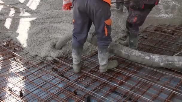 Arbeiter verteilen Beton über großen Stahlboden auf der Baustelle. - Filmmaterial, Video