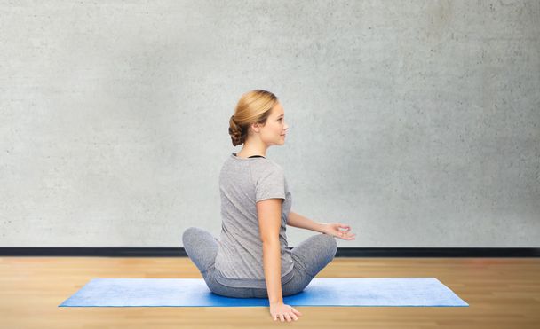 woman making yoga in twist pose on mat - Photo, image