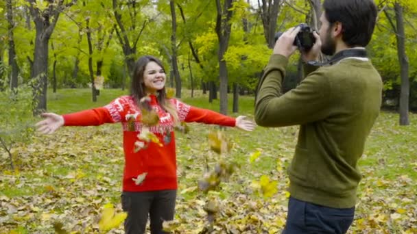 Kerl schießt auf seine Freundin, wirft ein paar gefallene Blätter in Zeitlupe hoch - Filmmaterial, Video
