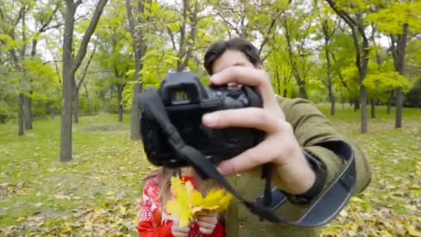 νεαρό ζευγάρι κάνοντας αυτοπορτρέτα με μια φωτογραφική μηχανή στο πάρκο φθινόπωρο - Πλάνα, βίντεο