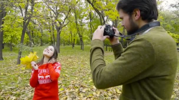 мужчина фотографирует молодую женщину в осеннем парке замедленной съемки
 - Кадры, видео