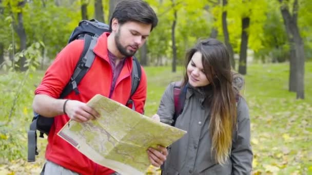 un par de mochileros mirando el mapa de papel en el bosque de otoño
 - Metraje, vídeo