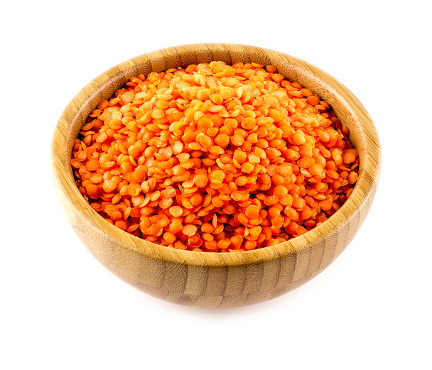 Deliziosi legumi di lenticchie rosse in ciotola di bambù contro lo schienale bianco
 - Foto, immagini