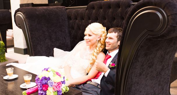 Νύφη και γαμπρός αγκαλιάζει. Νεόνυμφους κάθεται στον καναπέ και να αγκαλιάζει - Φωτογραφία, εικόνα
