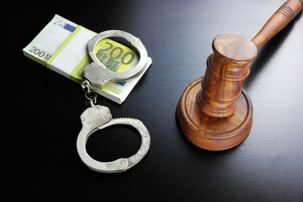 Richtergabel, Handschellen und Euro-Bargeld auf dem schwarzen Tisch - Foto, Bild