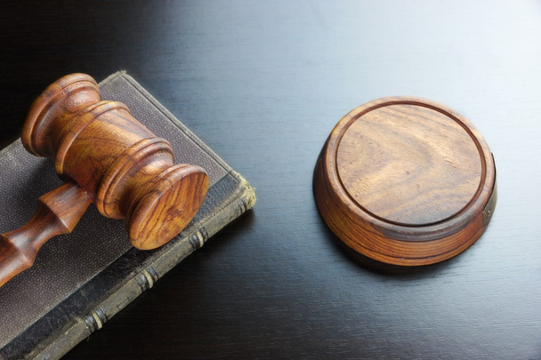 Судьи молоток и старая книга на черном деревянном столе
 - Фото, изображение