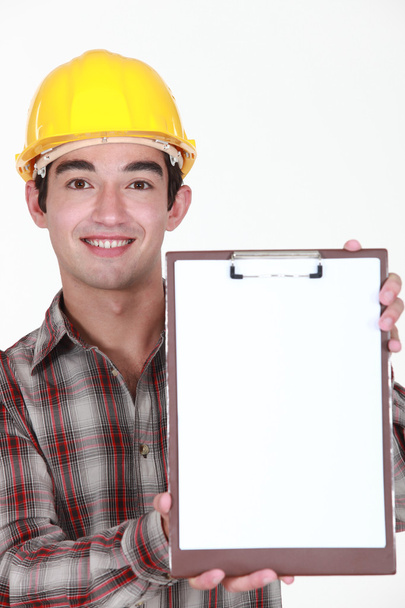 Young construction worker holding up a blank clipboard - Φωτογραφία, εικόνα