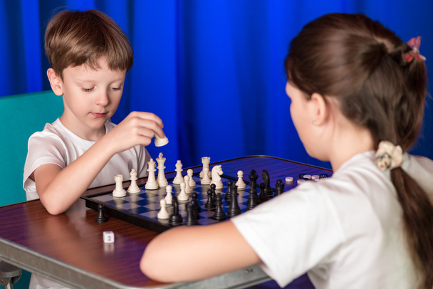Дети играют в настольную игру под названием шахматы
. - Фото, изображение
