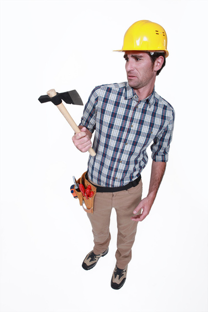 A handyman looking weirdly at his hatchet. - Foto, immagini