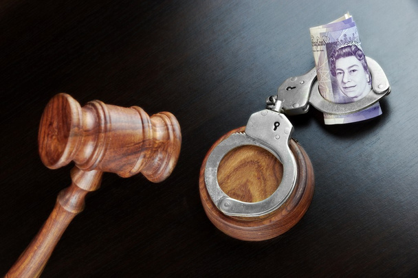 Richtergabel, Handschellen und britisches Bargeld auf dem schwarzen Tisch - Foto, Bild