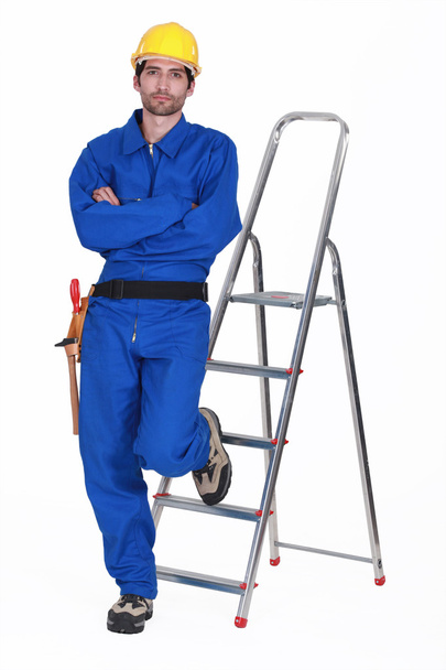 Laborer leaning on a ladder, studio shot - Foto, imagen