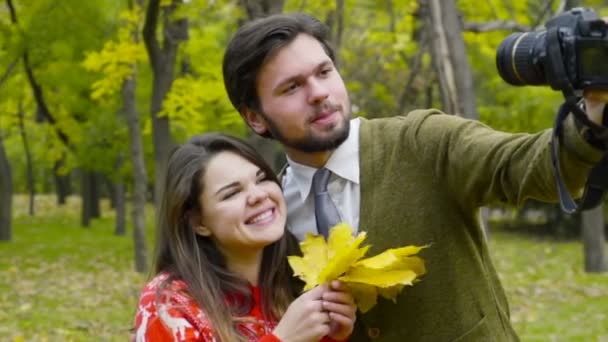 jovem casal fazendo selfie com uma câmera no parque de outono
 - Filmagem, Vídeo