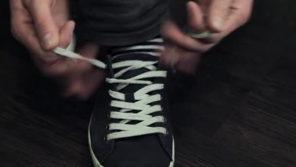 Mans hands tie white laces on right sport shoe. Zoom out. - Footage, Video