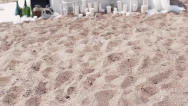 Witte tabel op zand strand aan zee ingericht. Kaarsen, flessen bloem - Video