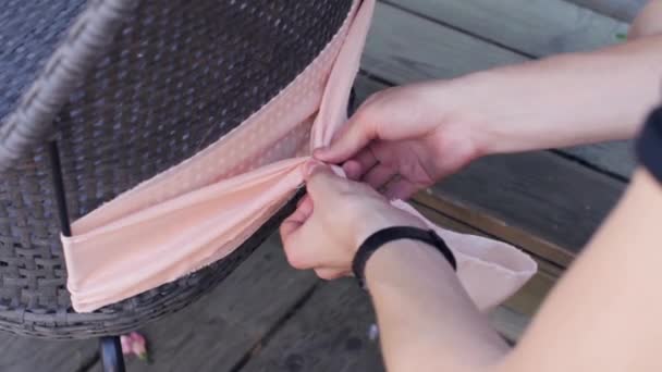 As mãos de mulheres decoram atrás da cadeira pelo têxtil rosa-claro no dia de verão
. - Filmagem, Vídeo