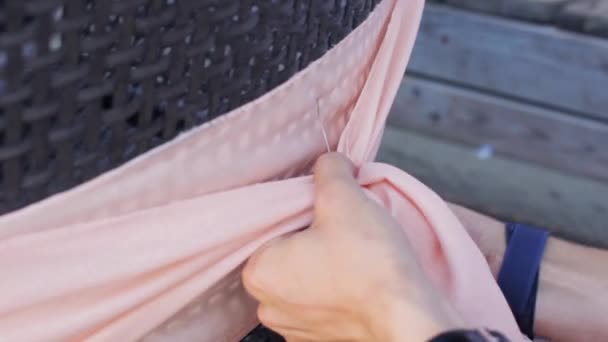 Dames handen versieren achterzijde stoel door licht roze textiel met draad in de zomer. - Video
