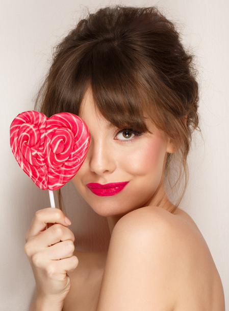 Fashion makeup. Beauty Girl Portrait holding Colorful lollipop. Hot red lips. - Fotó, kép