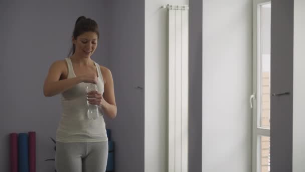 Meisje drinkt water uit een fles in een sportschool - Video